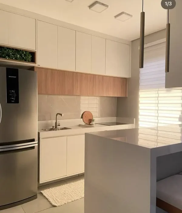 Cozinha planejada pequena e moderna, com armários brancos, bancada cinza e detalhes em madeira clara, otimizando o espaço com eletrodomésticos embutidos.